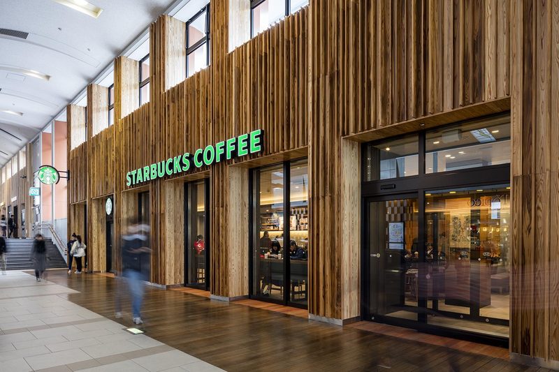 Alışveriş merkezi koridorunda ahşap kaplamalı Starbucks Coffee mağaza cephesi.